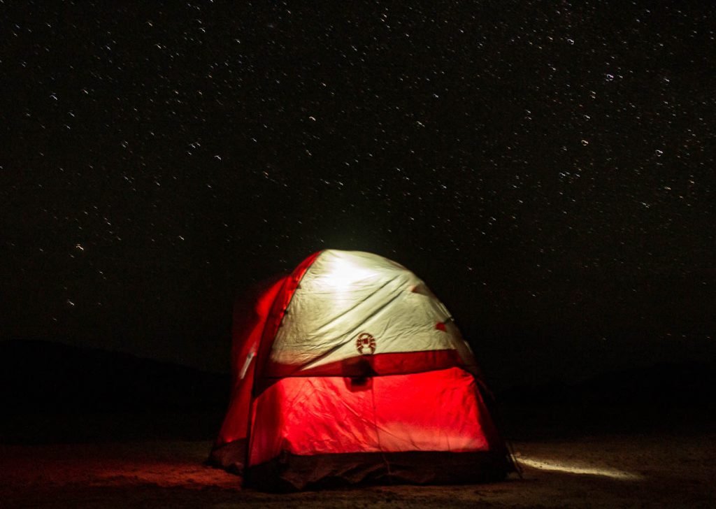 illuminated red tent with blurry stars in black sky above